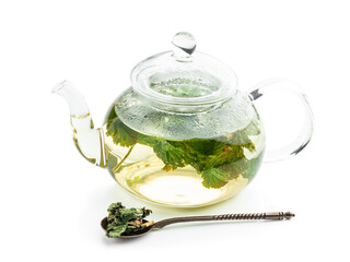 Tea in a glass teapot with leaves of black currant isolated on white