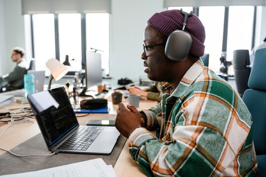 A man is programming on a laptop in the office
