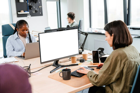 A woman uses a computer with white screen in the office