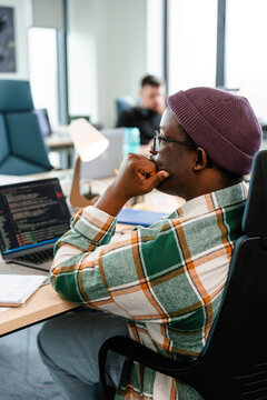 A man is programming on a laptop in the office