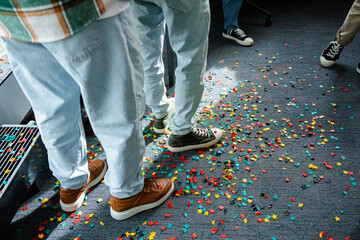 Men stand on the floor covered with confetti