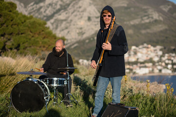 Bass guitarist and drummer play music in nature