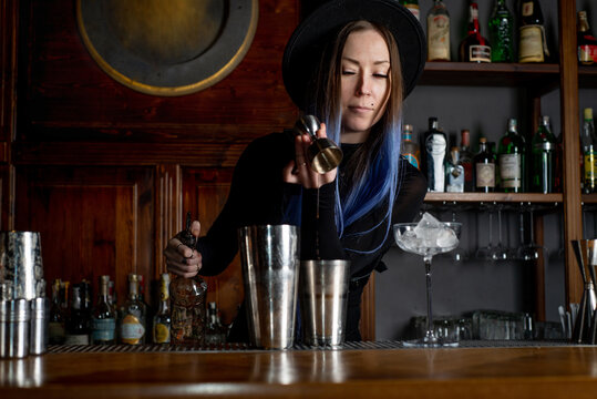 Woman bartender prepares cocktail at the bar counter