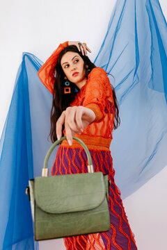 Supermodel with long hair showing crocodile skin bag and looking away