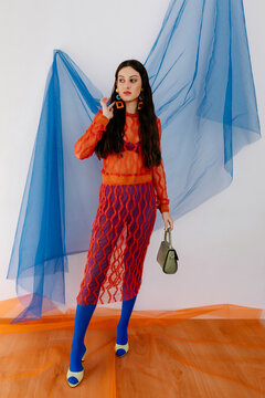 Stylish model with dark long hair standing in studio with handbag