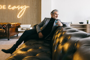 Mature stylish man relaxing on a luxury leather sofa