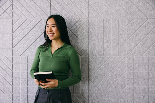 Asian professional with planner against textured backdrop