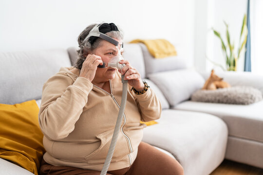 Senior woman putting on her CPAP mask.