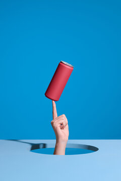Hand through the hole on light blue background with a can balance