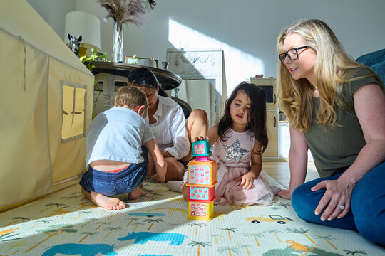 Lesbian couple enjoy playtime with their young family at home