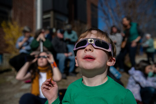 Young Child Watches Solar Eclipse with Safety Glasses on 