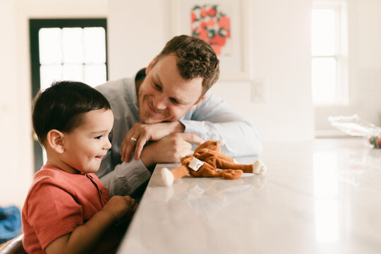father and toddler son sitting at kitchen island 
