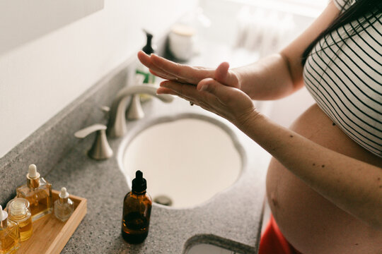 woman moisturizing her pregnant belly with natural oils 