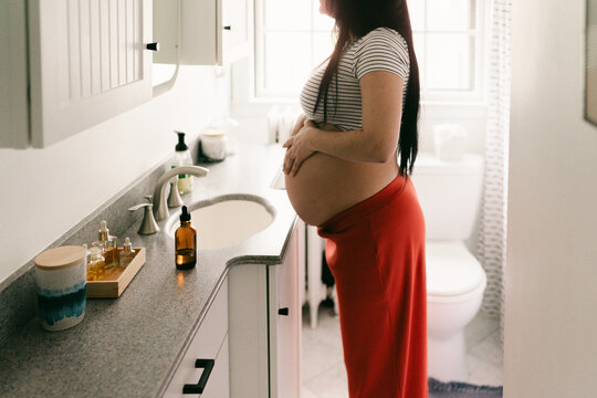 woman moisturizing her pregnant belly with natural oils 