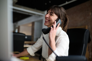 Smiling Business woman talking on phone at desk