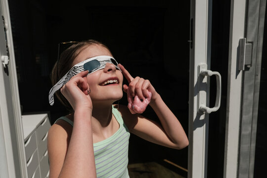 Young girl looks at solar eclipse with protective glasses
