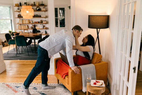  pregnant woman sitting in armchair, husband brings snack