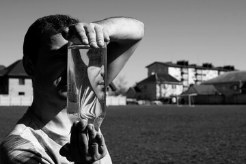 Man looking through transparent glass vase with water
