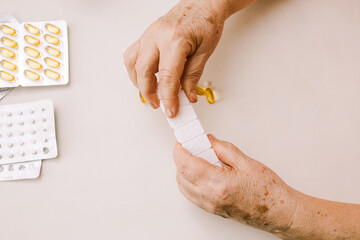 The hands of a man putting vitamins and supplements in a pillbox.