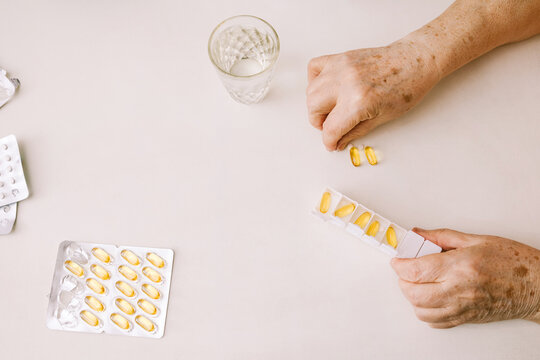 The hands of a man putting vitamins and supplements in a pillbox.