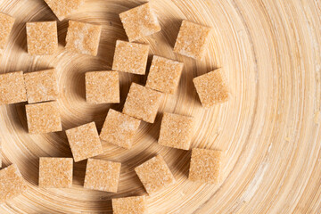 Cubes of refined cane sugar on wooden background.