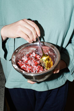 Person mixing fresh berries and cream in a bowl