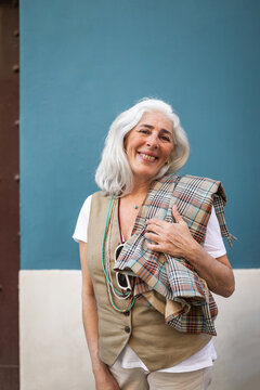 mature woman with white hair next to a turquoise blue wall