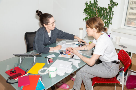 Two Designers Collaborating at a Cluttered Desk

