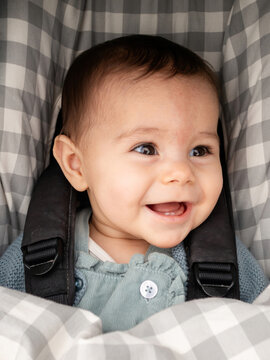Joyful baby in car seat with checkered pattern