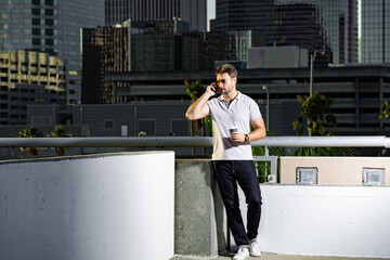 Portrait of handsome male model chatting on phone outdoor. Stylish man talking on phone dressed in...