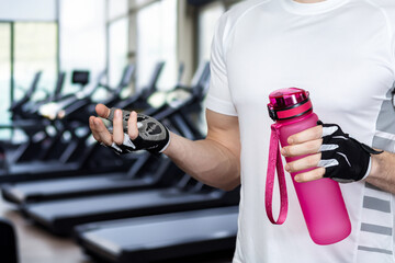 An athlete with a bottle of water stands .