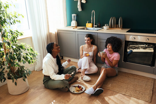 Female roommates having breakfast in kitchen