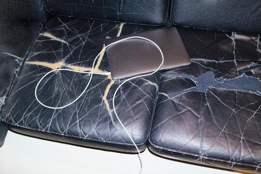 Silver laptop with wire charger in a broken sofa in business office 