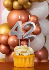 Cupcake with birthday candle on balloons background - Number 42
