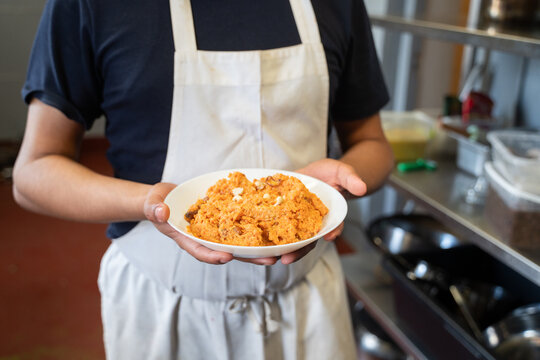 Anonymous Cook Holding Carrot Halwa On The Plate