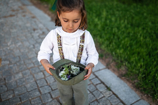 girl holding wildflowers in a hat