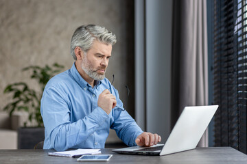 Mature businessman working on laptop in modern office, showing professionalism and concentration