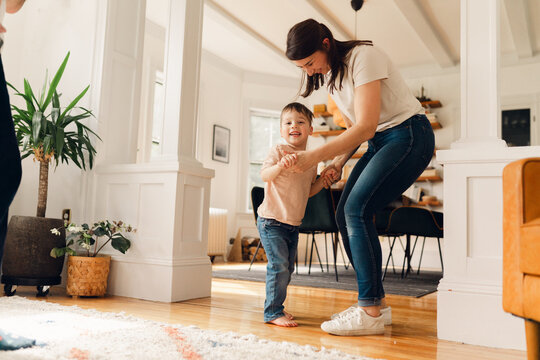 mother and little boy dancing in living room 