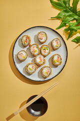 sushi enplatado sobre un fondo amarillo con salsa y vegetacion 