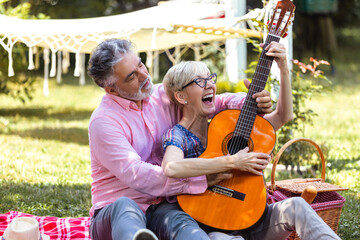 Music, guitar and a senior couple on picnic in park, romance in retirement.