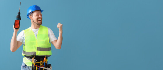 Happy male builder with drill on blue background