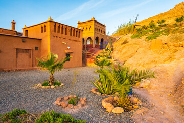 Clay buildings and gardens of traditional riad kasbah guesthouse at sunrise in Ait Ben Haddou...