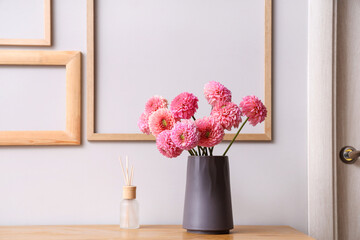 Vase of beautiful pink dahlias with diffuser on commode in living room