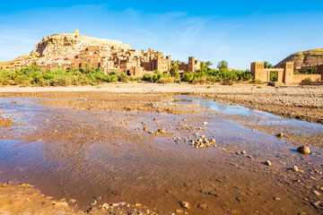 View of river and Ksar Ait Ben Haddou, old Berber adobe-brick village or kasbah in green oasis with...