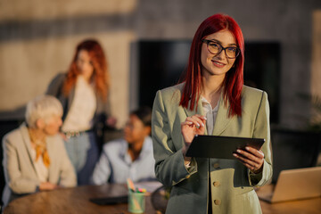 Portrait of smiling female entrepreneur using tablet at boardroom.