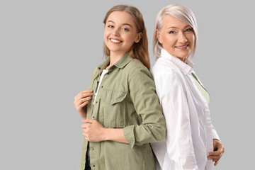 Young woman with her mother on light background