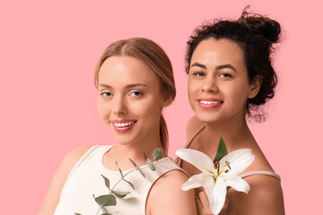 Beautiful young women with lily flower and eucalyptus on pink background