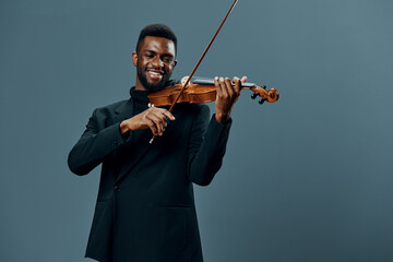 African American musician playing violin in elegant suit against gray background, artistic...