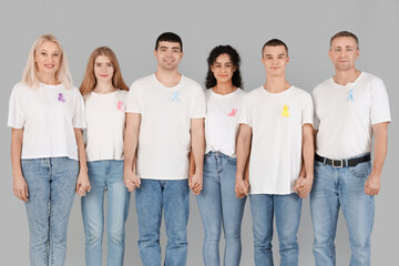 People with different awareness ribbons on light background. World Cancer Day