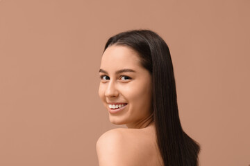 Young dark-haired woman on beige background